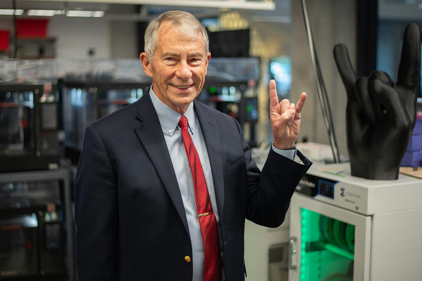 Texas Engineering alumnus Chuck Corley doing hook 'em horns hand sign in a lab