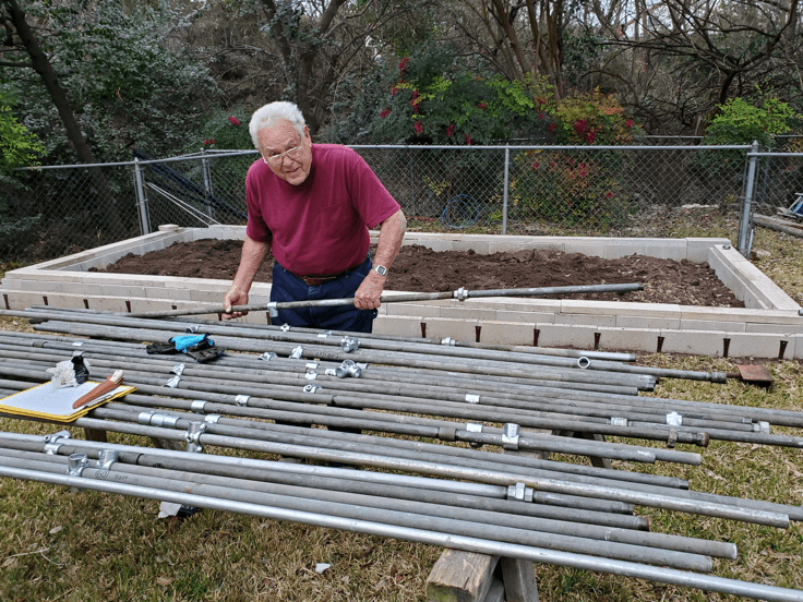 Lew Griffith working with lengths of pipe in backyard