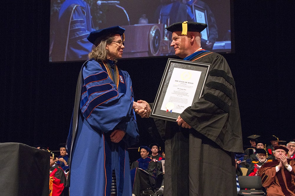 Former Cockrell School of Engineering Dean Sharon Wood shakes hands with a distinguished engineering graduate award recipient at commencement ceremony