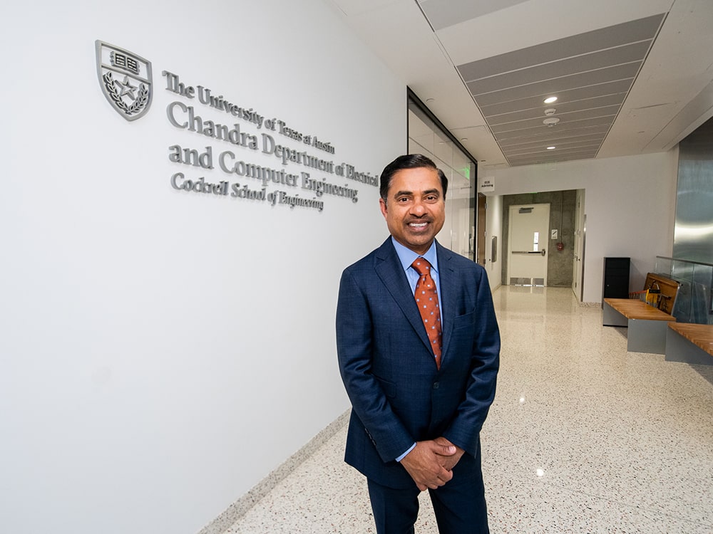 Sanjay Chandra smiling next to the new building engraving for Chandra Family Department of Electrical and Computer Engineering