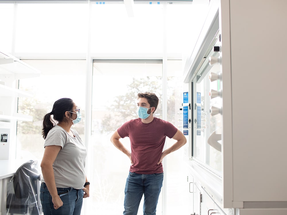 Two Texas engineers talking while wearing face masks