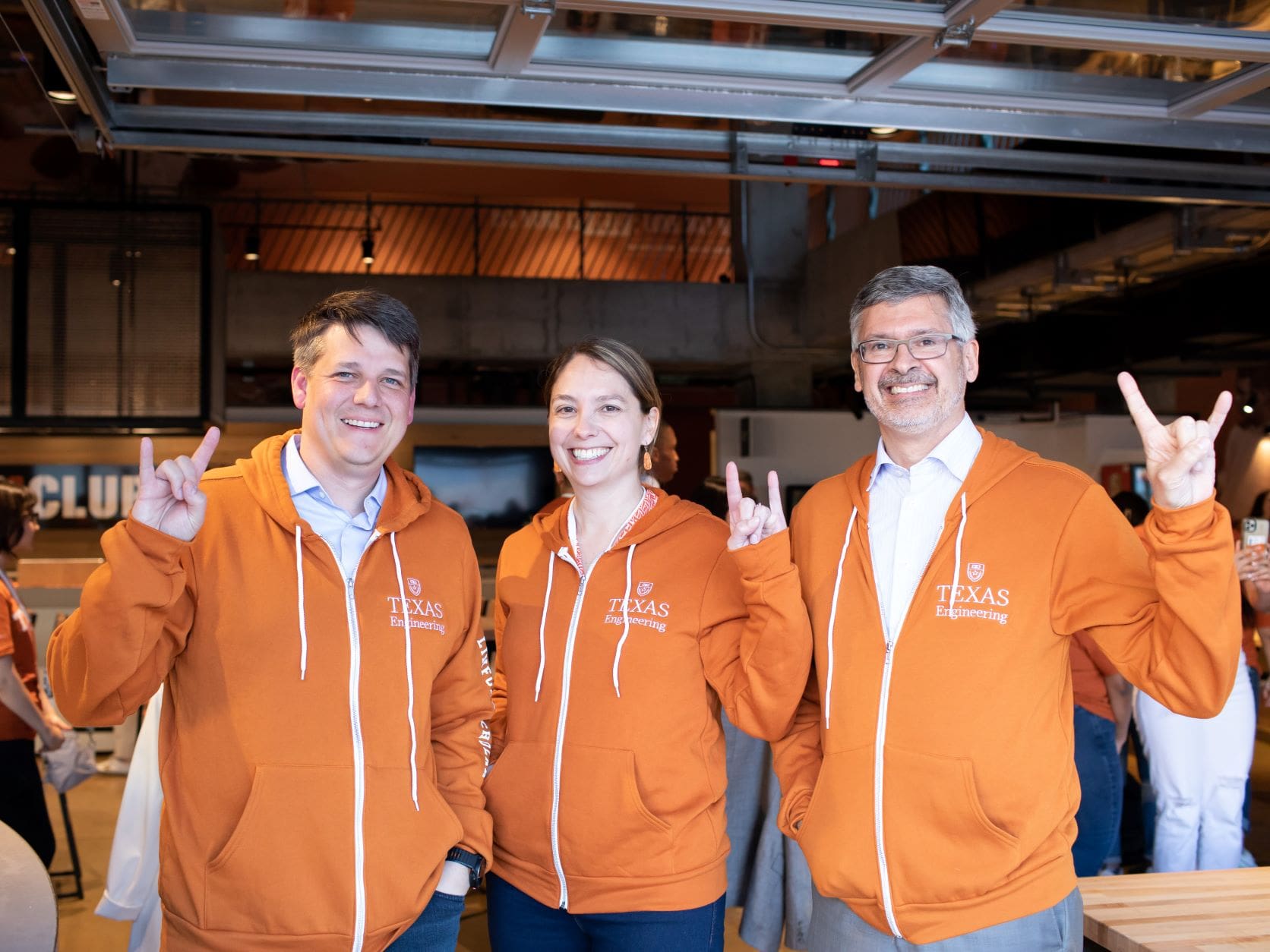 Alumnus Michael and Erika Linford and Cockrell School of Engineering Dean Roger Bonnecaze wearing UT Austin hoodies