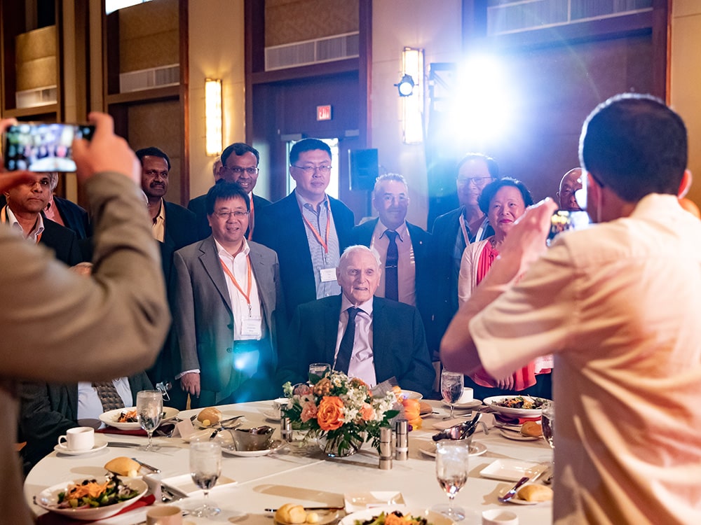 John Goodenough posing for photos with small crowd in dining room