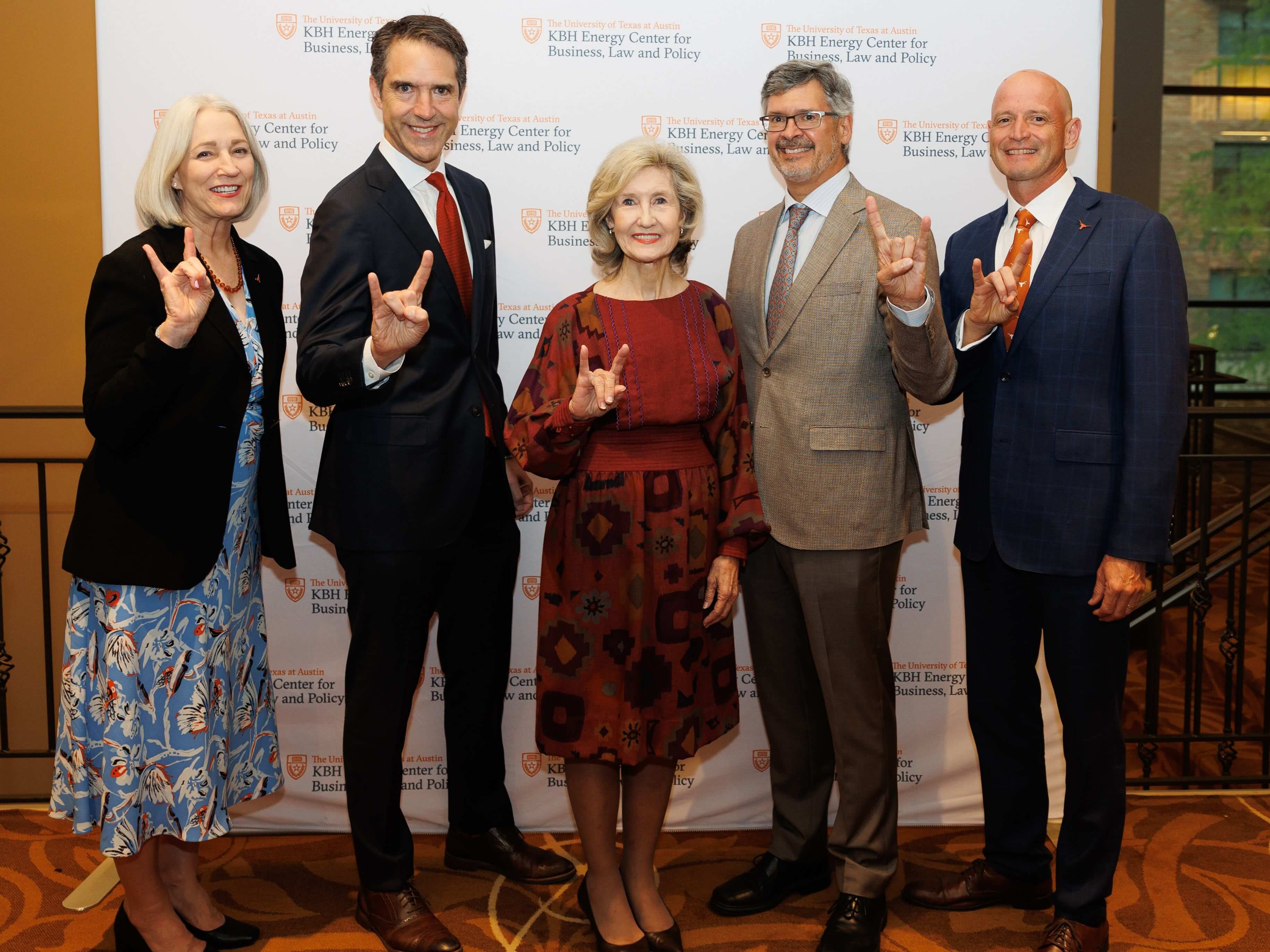 Roger Bonnecaze and UT Austin alumni doing hook 'em horn hand signs in front of KBH Energy Center backdrop