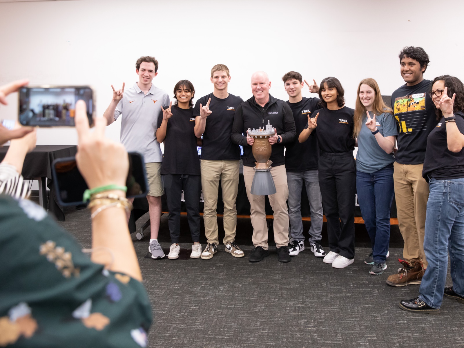 Texas engineering students wearing TREL t-shirts smiling with trophy