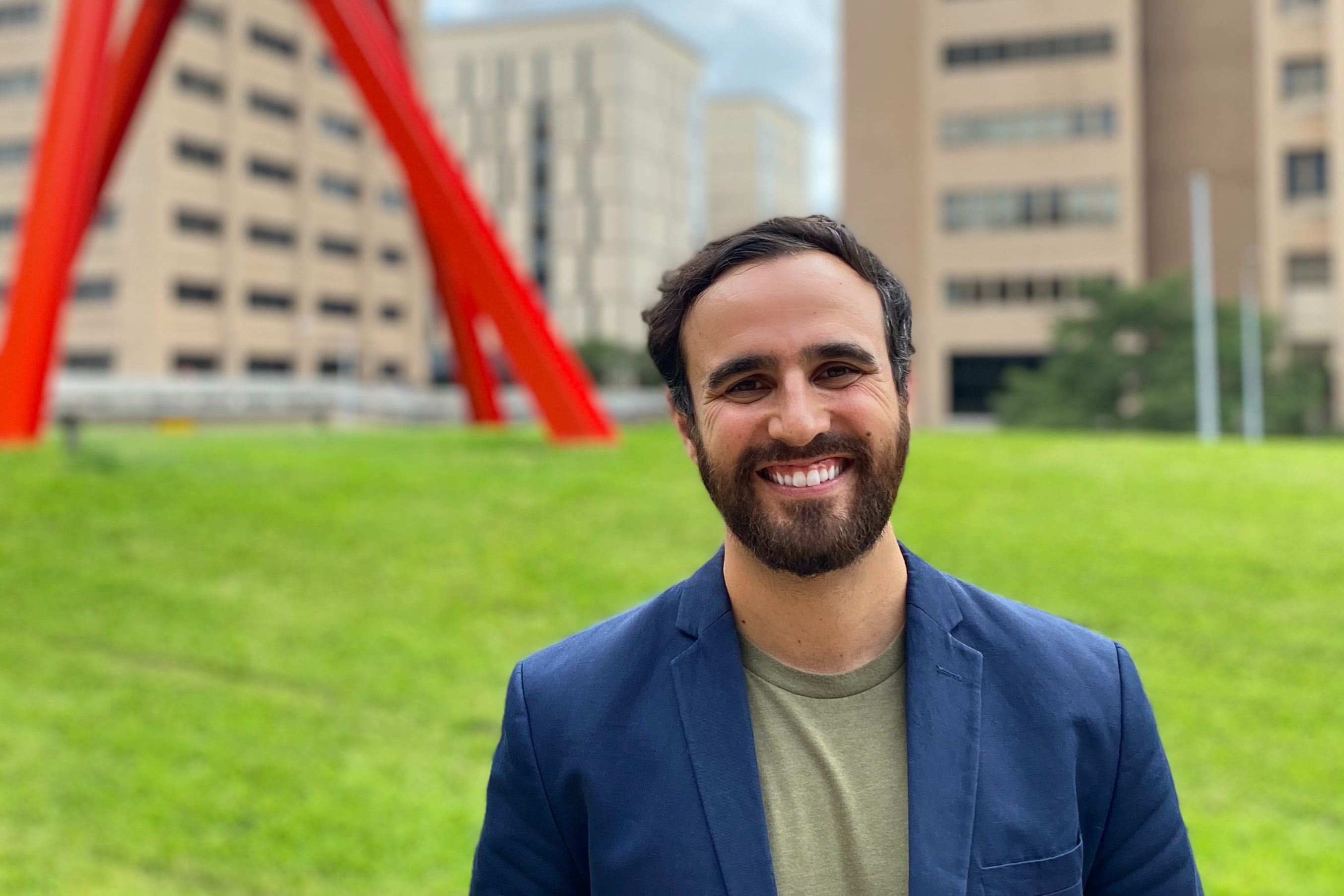 TX engineering professor Joaquin Resasco smiling in front of the clock knot sculpture