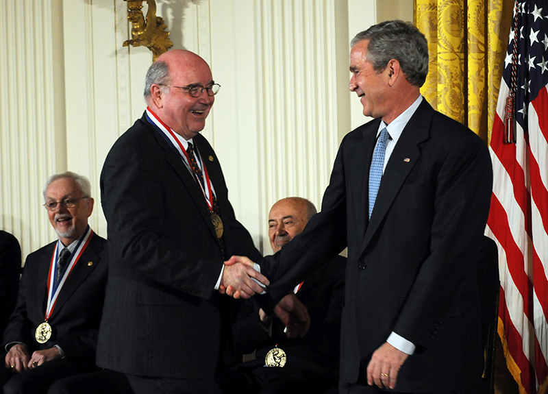 Grant Willson shaking hands with former President George W. Bush on a stage with other National Medal winners