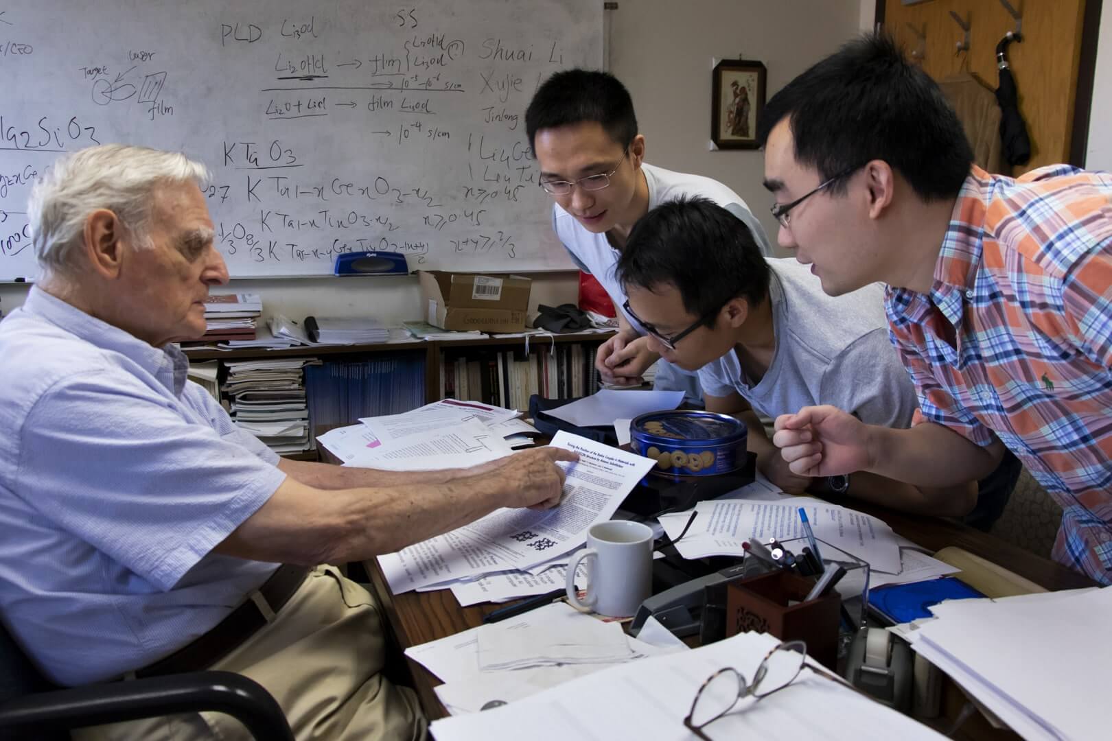 John Goodenough talking to a group of students over a pile of papers