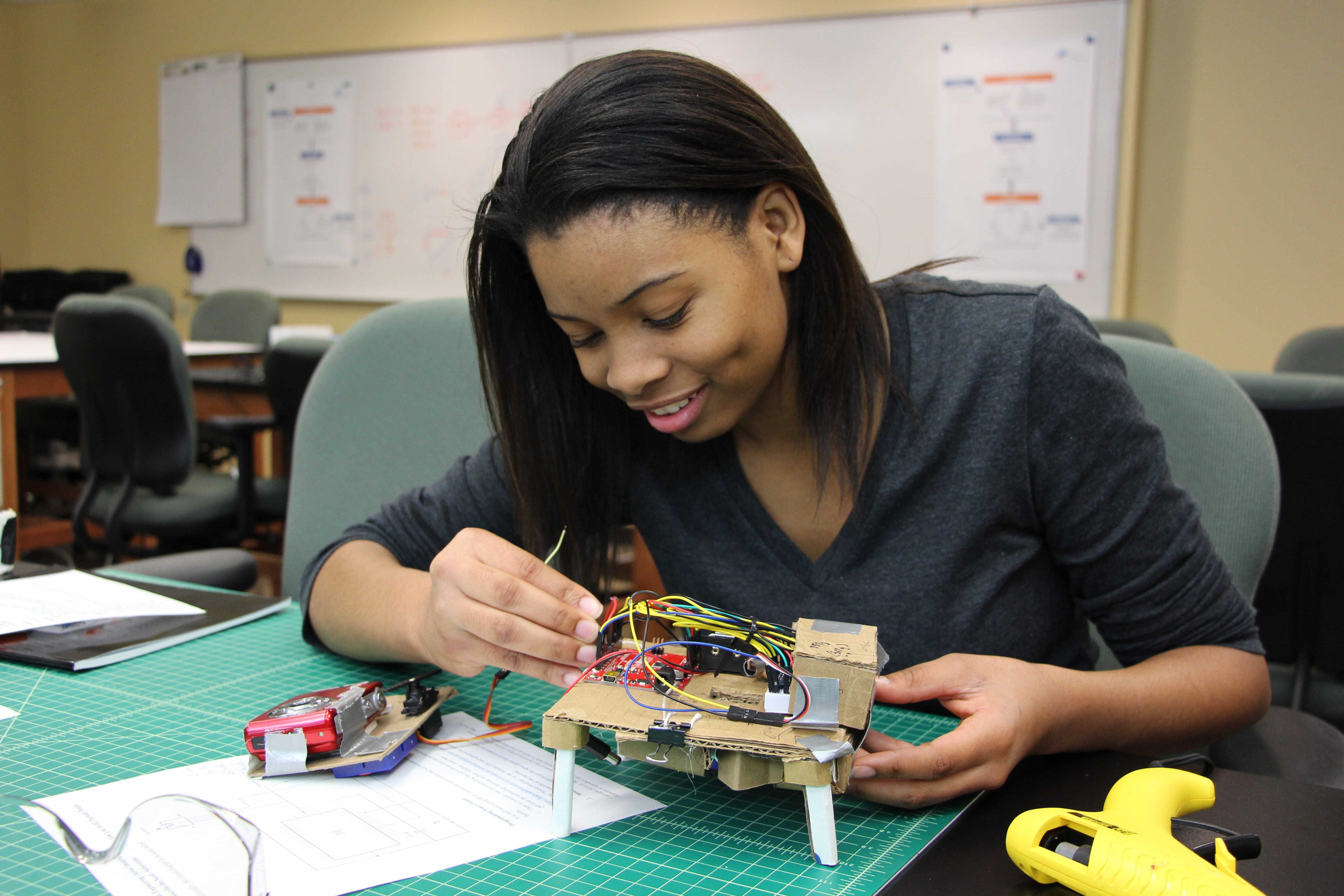 Young woman examining part of a machine with exposed wiring