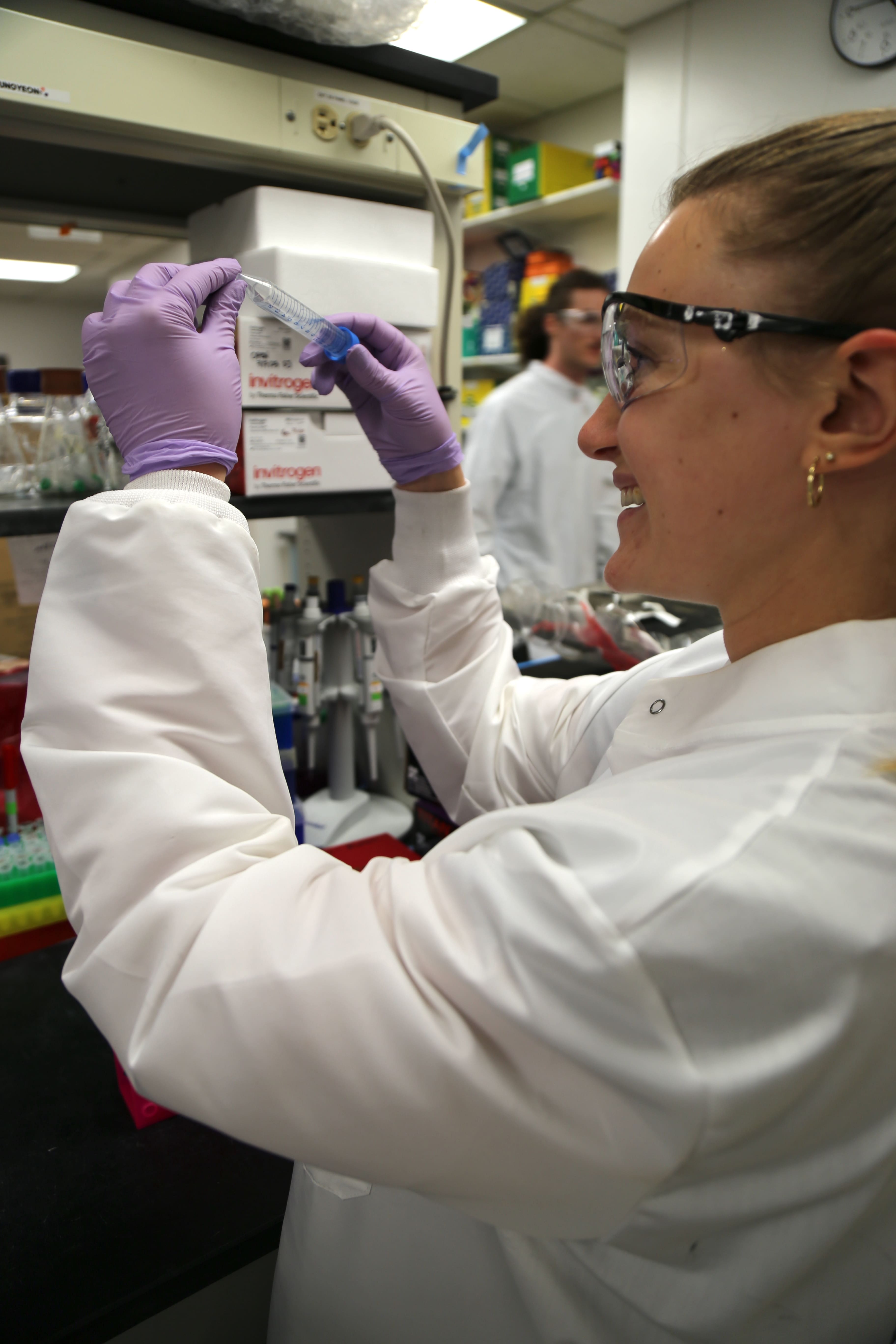 A Texas engineering student wearing lab safety apparel while holding a test tube