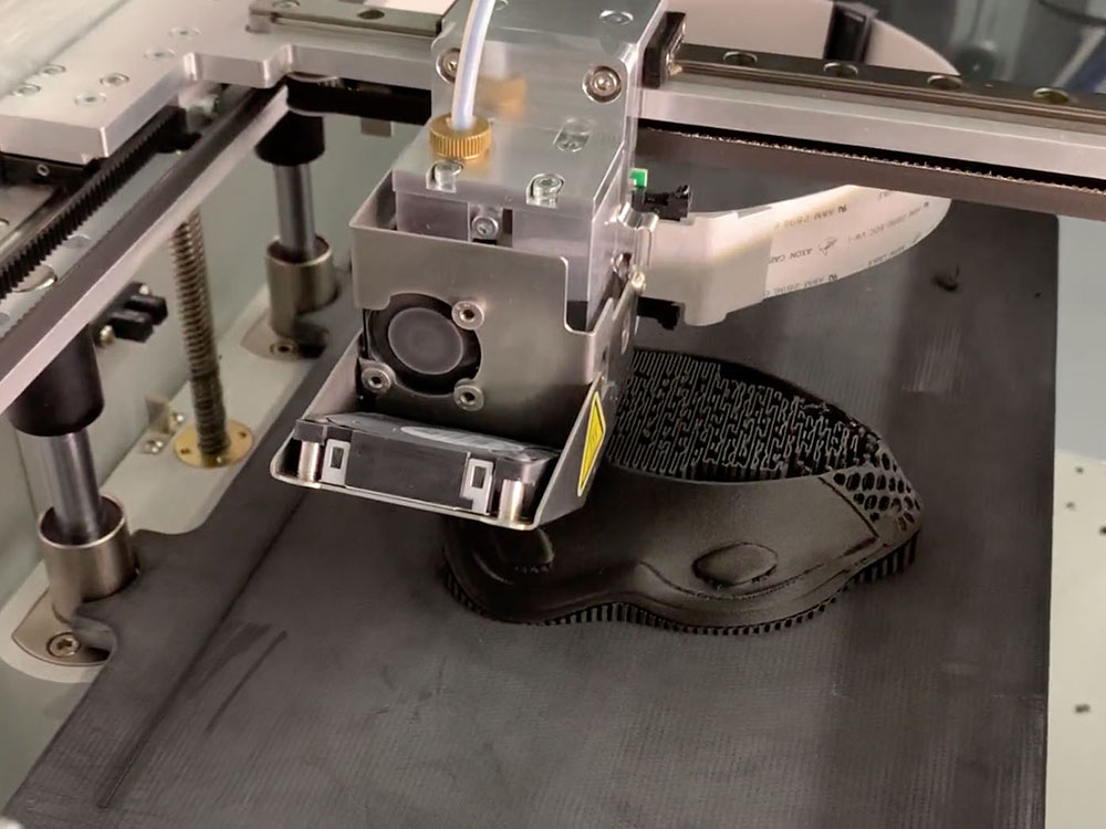 Photo of a 3D printer beginning to print a mask with black plastic.