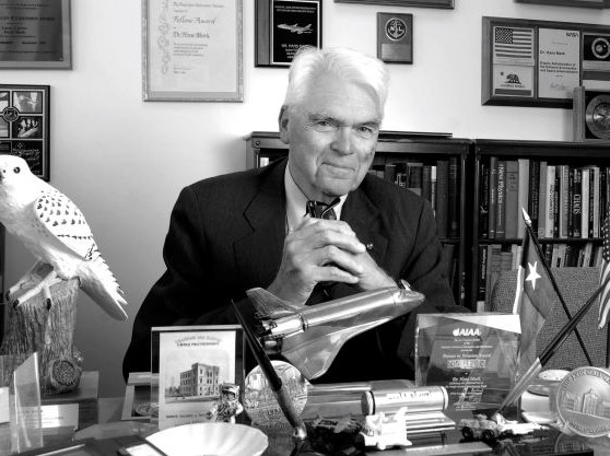black and white photo of Hans Mark smiling in his office