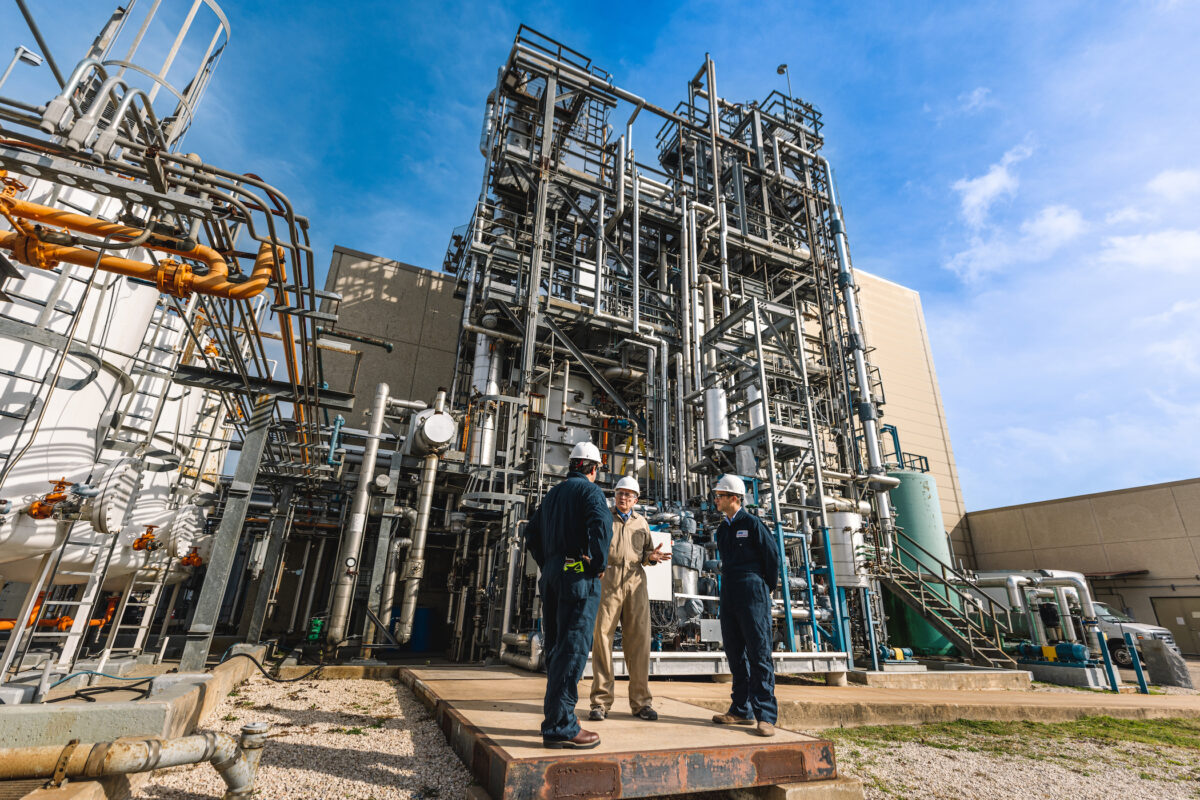 Three men in hardhats standing in front of Rochelle Carbon Capture equipment