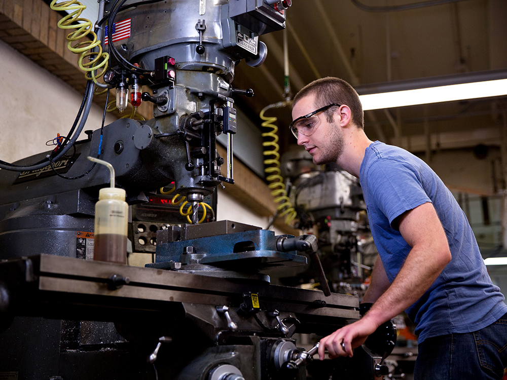 student wearing safety goggles operating heavy machinery