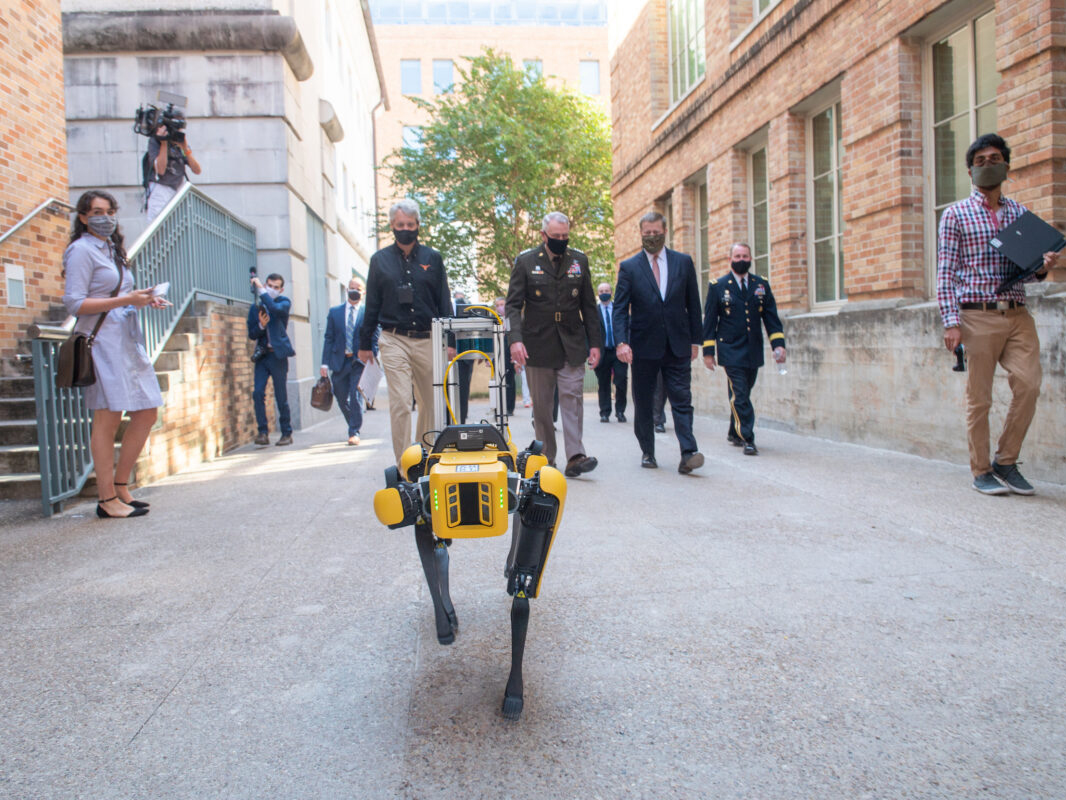 group of people walking behind robot