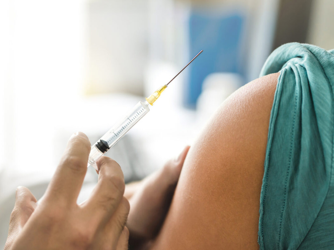 Doctor holding needle next to patient's bare arm