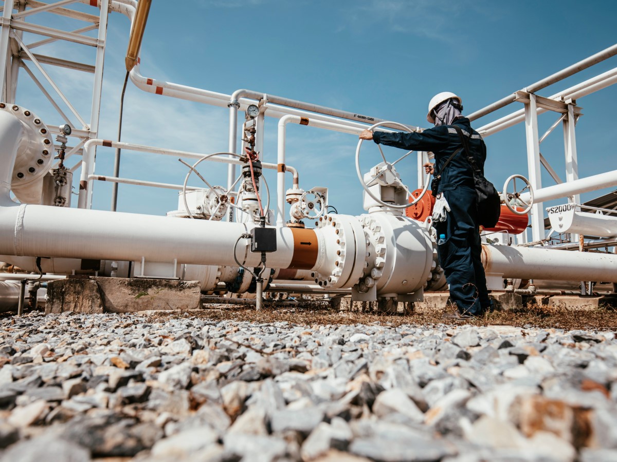 Production operator opening ball valve at pipeline oil and gas wellhead remote platform to control gases and crude oil process petroleum