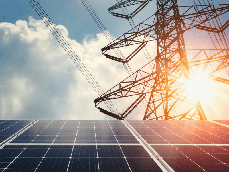 Power grid at sunset with sun shining on solar panels