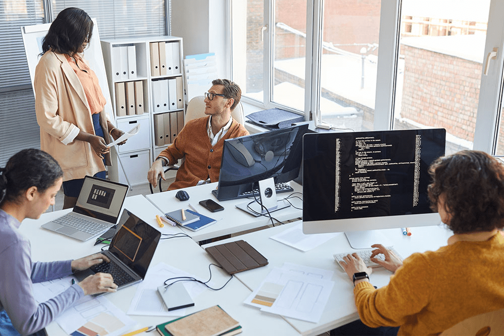 TXEEE students collaborate around table and computers