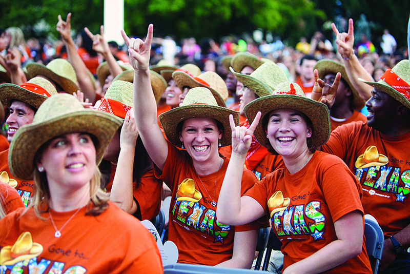 Smiling Texas engineering students doing hook 'em horns hand sign at Gone to Texas event