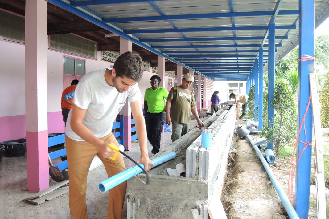 Texas engineering student sawing a piece of pipe from a building under construction