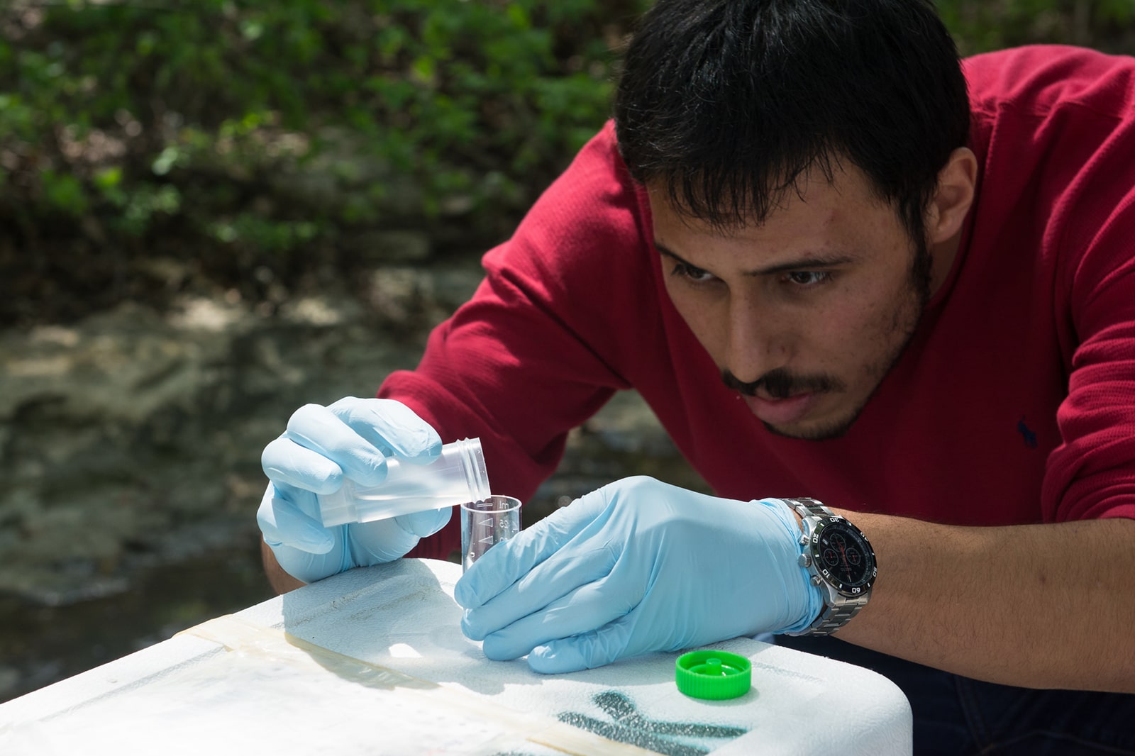 Texas environmental engineering student pouring liquid into beaker outside